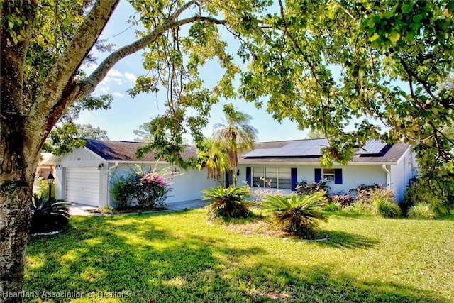 single story home featuring solar panels, a garage, and a front yard