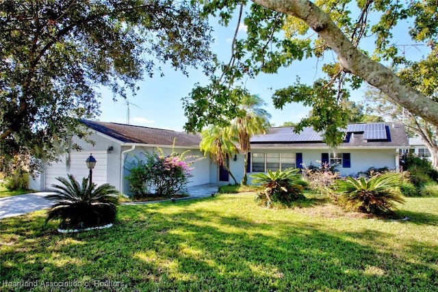 ranch-style house featuring solar panels, a garage, and a front lawn