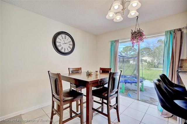 dining area featuring a chandelier, a textured ceiling, and light tile patterned flooring