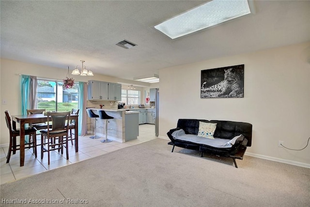 interior space featuring a skylight, light tile patterned flooring, a textured ceiling, and an inviting chandelier