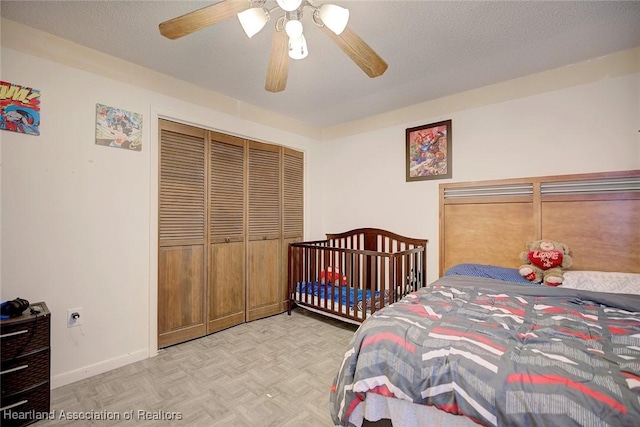 bedroom featuring a textured ceiling, light parquet flooring, a closet, and ceiling fan