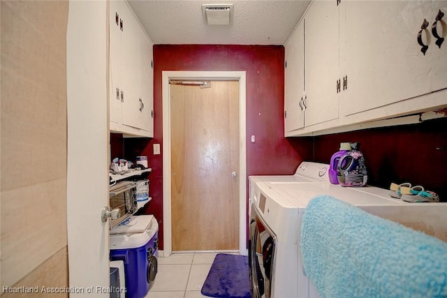 washroom featuring cabinets, light tile patterned floors, a textured ceiling, and separate washer and dryer