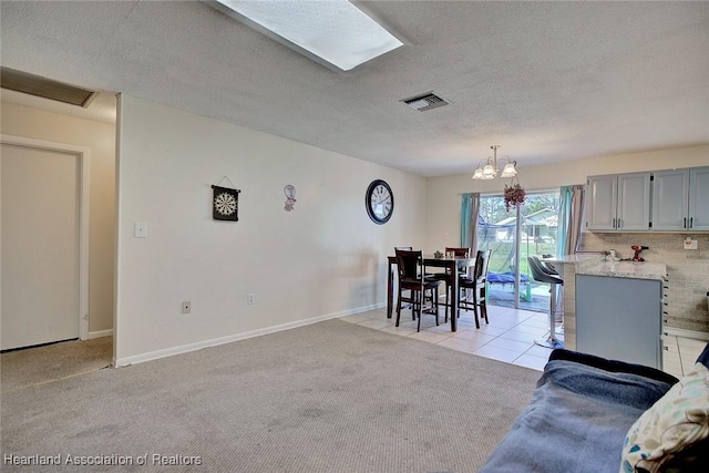 dining area with a textured ceiling, light colored carpet, and a notable chandelier