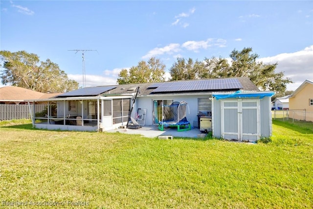 back of property with a sunroom, solar panels, a trampoline, and a yard