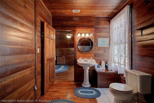 bathroom featuring wooden walls, ceiling fan, wooden ceiling, and toilet