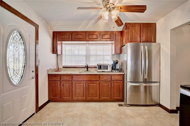 kitchen with ceiling fan, stainless steel fridge, light tile patterned floors, and sink