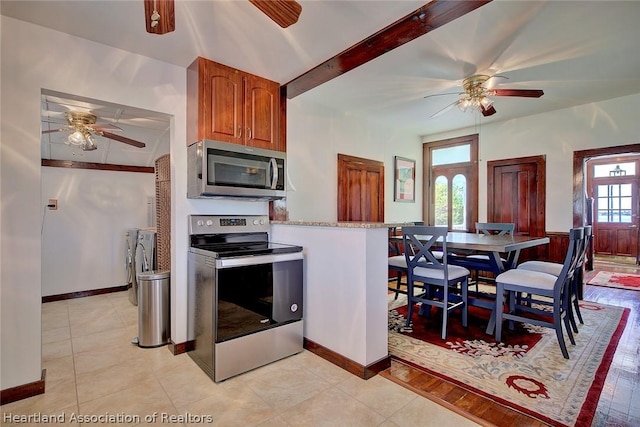 kitchen featuring beam ceiling, light tile patterned flooring, stainless steel appliances, and french doors