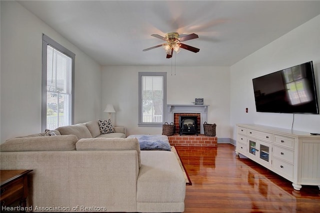 living room with hardwood / wood-style floors, a wood stove, and ceiling fan