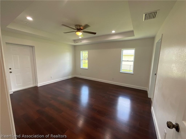 unfurnished room with dark hardwood / wood-style floors, ceiling fan, and a tray ceiling