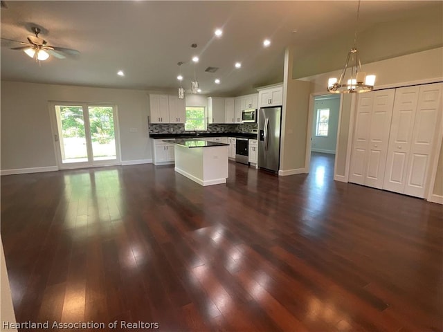 kitchen with appliances with stainless steel finishes, vaulted ceiling, decorative light fixtures, a center island, and white cabinetry