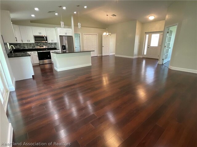 kitchen featuring white cabinetry, a center island, stainless steel appliances, backsplash, and pendant lighting