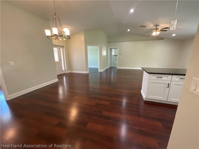 interior space featuring ceiling fan with notable chandelier, dark wood-type flooring, and lofted ceiling