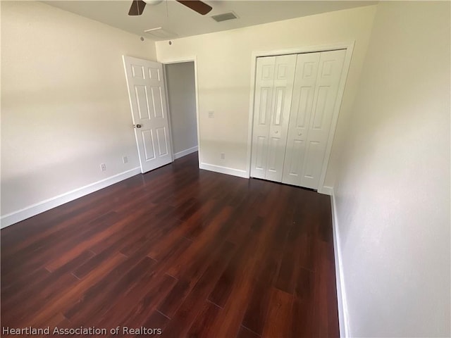 unfurnished bedroom with ceiling fan, dark hardwood / wood-style floors, and a closet