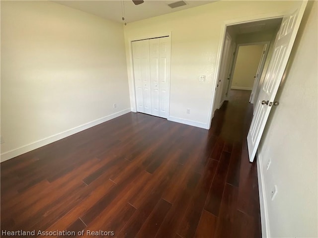 unfurnished bedroom featuring ceiling fan, a closet, and dark wood-type flooring