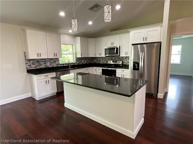 kitchen featuring pendant lighting, a kitchen island, white cabinets, and stainless steel appliances