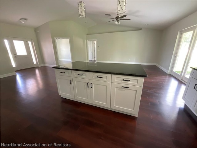 kitchen with ceiling fan, dark wood-type flooring, pendant lighting, white cabinets, and a center island