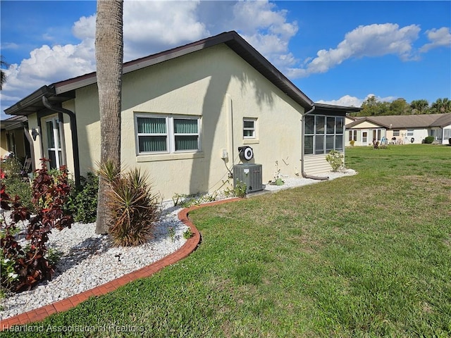 view of side of home featuring a sunroom, a lawn, and central air condition unit