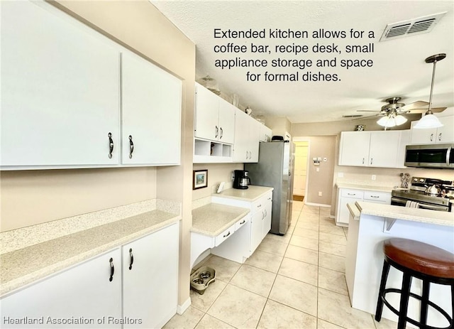 kitchen with white cabinetry, stainless steel appliances, a kitchen bar, and decorative light fixtures