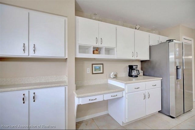 kitchen featuring light tile patterned flooring, stainless steel fridge, and white cabinets