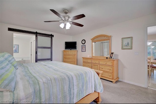 carpeted bedroom with a barn door and ceiling fan