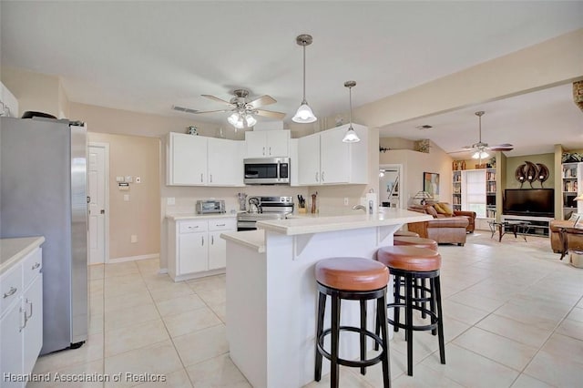 kitchen with light tile patterned flooring, decorative light fixtures, white cabinetry, a kitchen bar, and stainless steel appliances