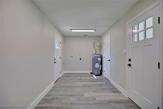 laundry area with electric water heater and light wood-type flooring