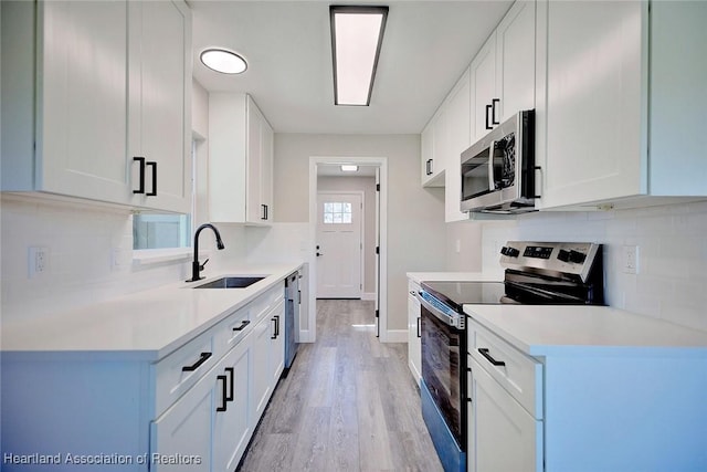 kitchen with white cabinets, stainless steel appliances, light hardwood / wood-style flooring, and sink