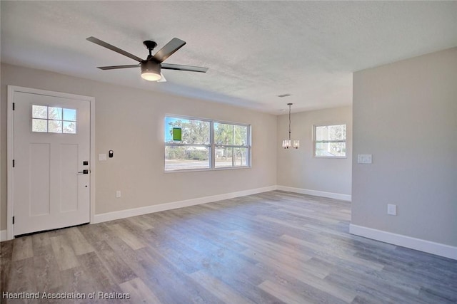 foyer entrance featuring a textured ceiling, ceiling fan with notable chandelier, and light hardwood / wood-style floors