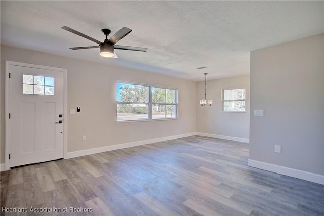 foyer with hardwood / wood-style floors, ceiling fan with notable chandelier, and a textured ceiling