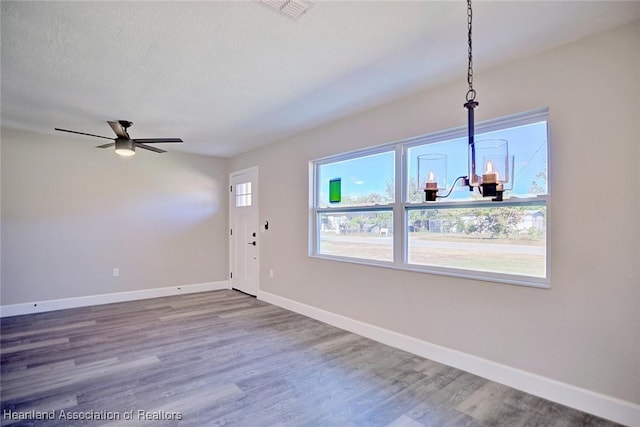 interior space with ceiling fan with notable chandelier, hardwood / wood-style flooring, and a healthy amount of sunlight