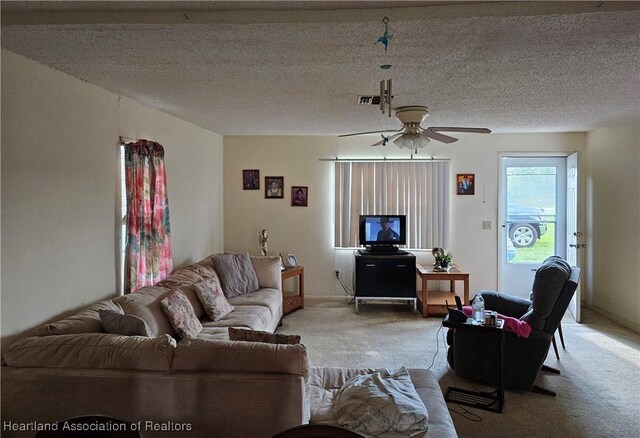 carpeted living room featuring ceiling fan and a textured ceiling