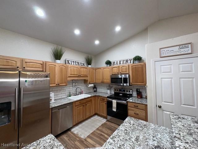 kitchen featuring tasteful backsplash, stainless steel appliances, sink, and light stone counters