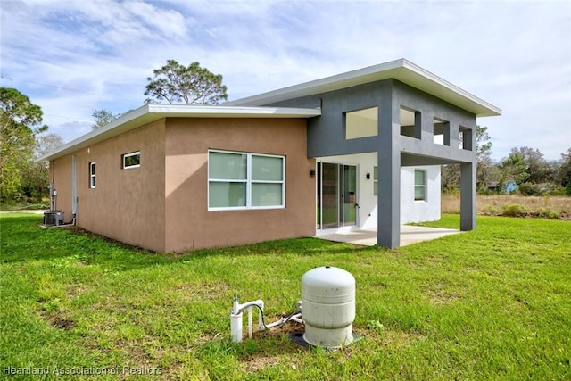 rear view of property featuring central AC, a patio area, and a lawn