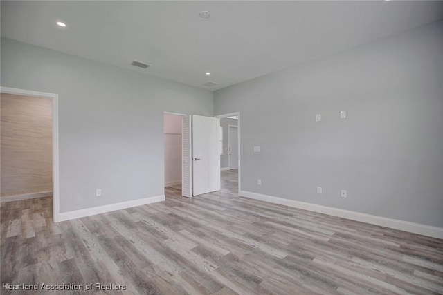 unfurnished bedroom with a spacious closet, a closet, and light hardwood / wood-style floors