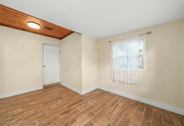 empty room featuring baseboards, visible vents, and wood finish floors