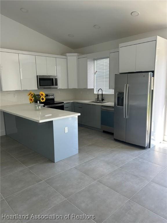 kitchen featuring white cabinetry, sink, kitchen peninsula, vaulted ceiling, and appliances with stainless steel finishes