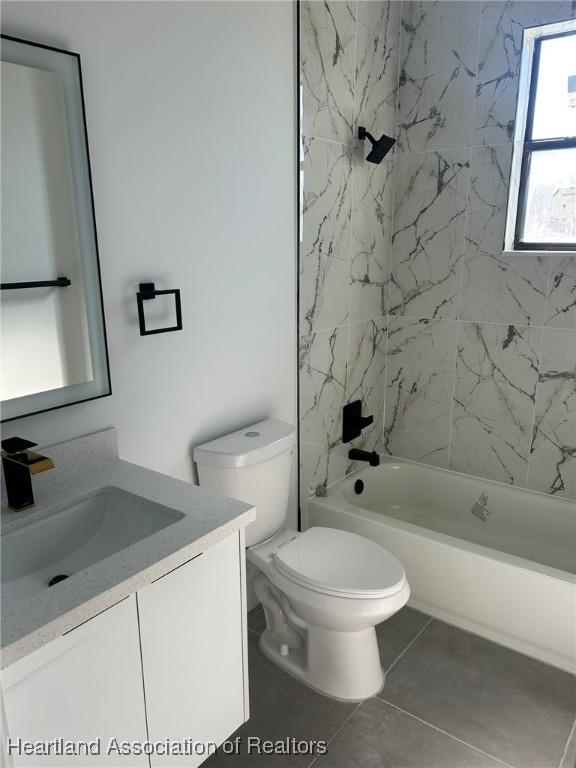 full bathroom featuring tile patterned floors, vanity, toilet, and tiled shower / bath combo