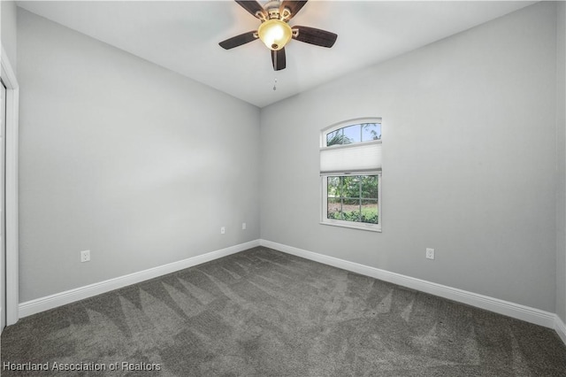 spare room featuring ceiling fan and dark colored carpet