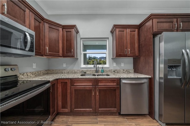 kitchen featuring sink, light stone counters, crown molding, light wood-type flooring, and appliances with stainless steel finishes