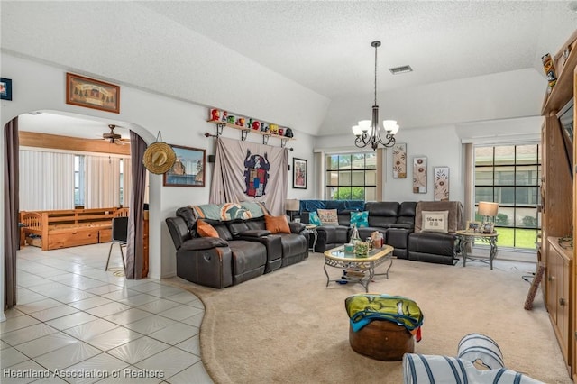 carpeted living room with ceiling fan with notable chandelier, a healthy amount of sunlight, lofted ceiling, and a textured ceiling