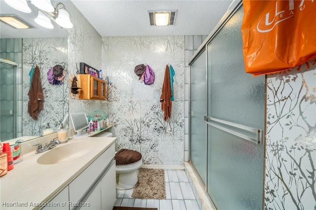 bathroom featuring vanity, a textured ceiling, toilet, and a shower with shower door