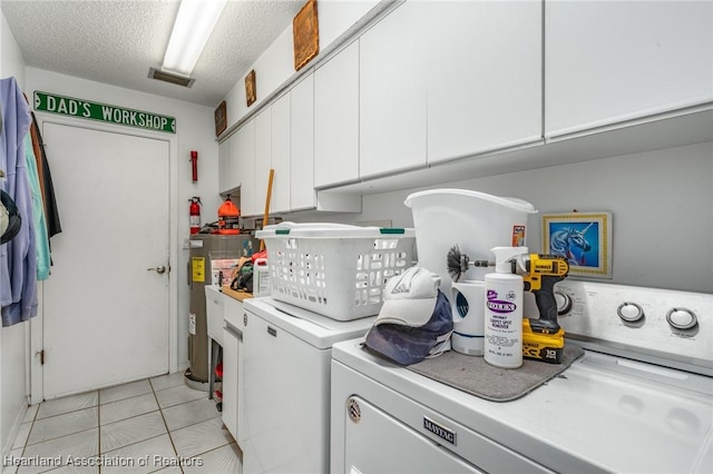 clothes washing area featuring cabinets, washing machine and dryer, electric water heater, and a textured ceiling