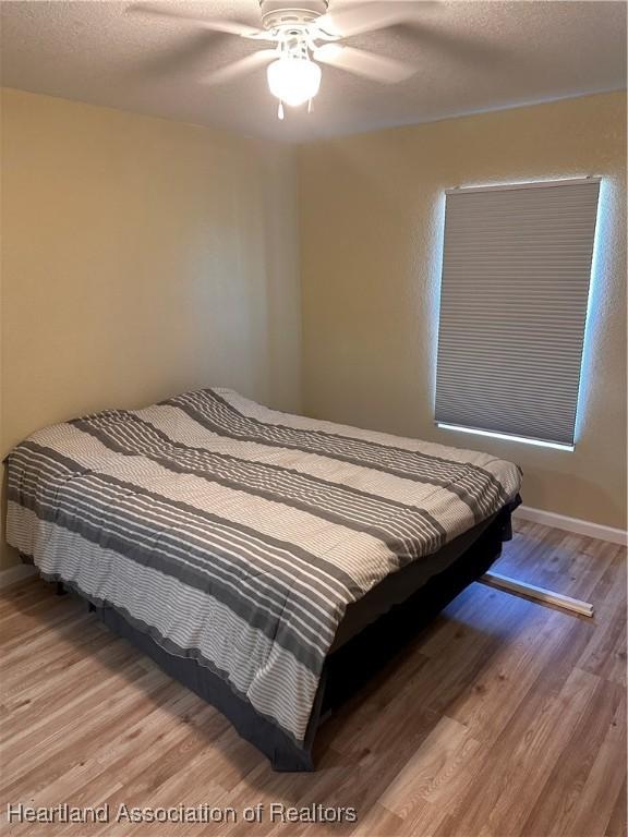 2633 W Newton Rd, Avon Park, FL 33825 - bedroom with baseboards, wood finished floors, a ceiling fan, and a textured ceiling