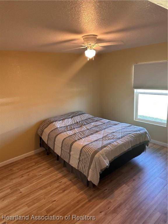 2633 W Newton Rd, Avon Park, FL 33825 - bedroom with baseboards, wood finished floors, ceiling fan, and a textured ceiling