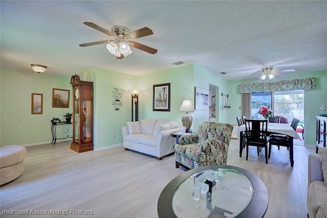 living area with baseboards, a ceiling fan, and light wood finished floors