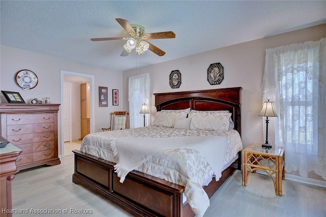 bedroom featuring light wood-style floors, a textured ceiling, and ceiling fan