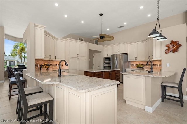 kitchen with a sink, backsplash, a peninsula, and stainless steel appliances