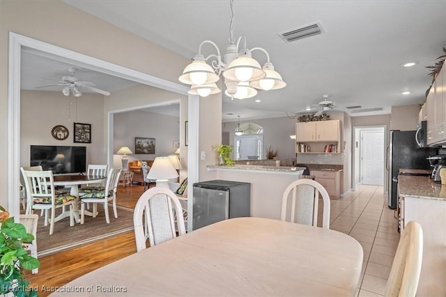 tiled dining space featuring ceiling fan with notable chandelier