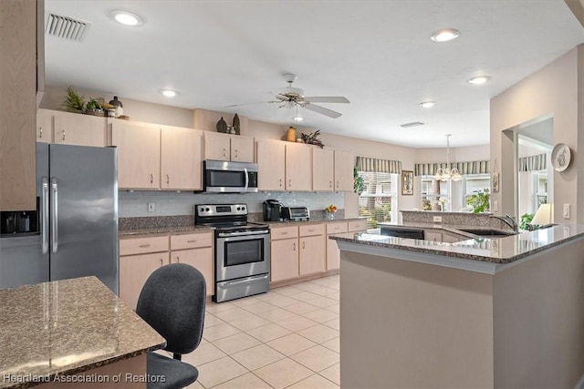 kitchen featuring stone counters, appliances with stainless steel finishes, hanging light fixtures, light tile patterned floors, and light brown cabinets