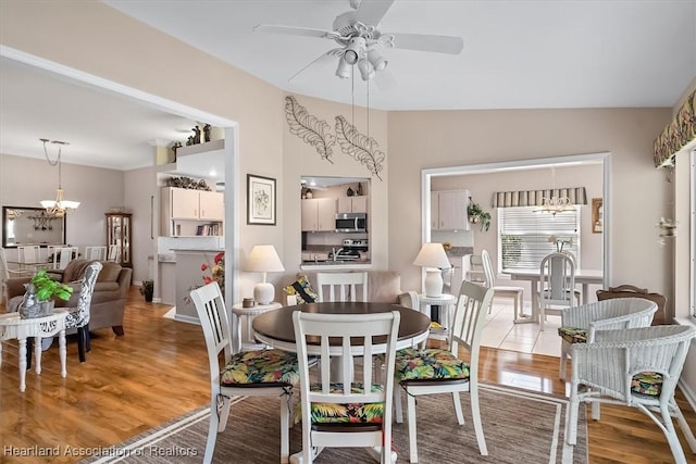 dining space with wood-type flooring and ceiling fan with notable chandelier